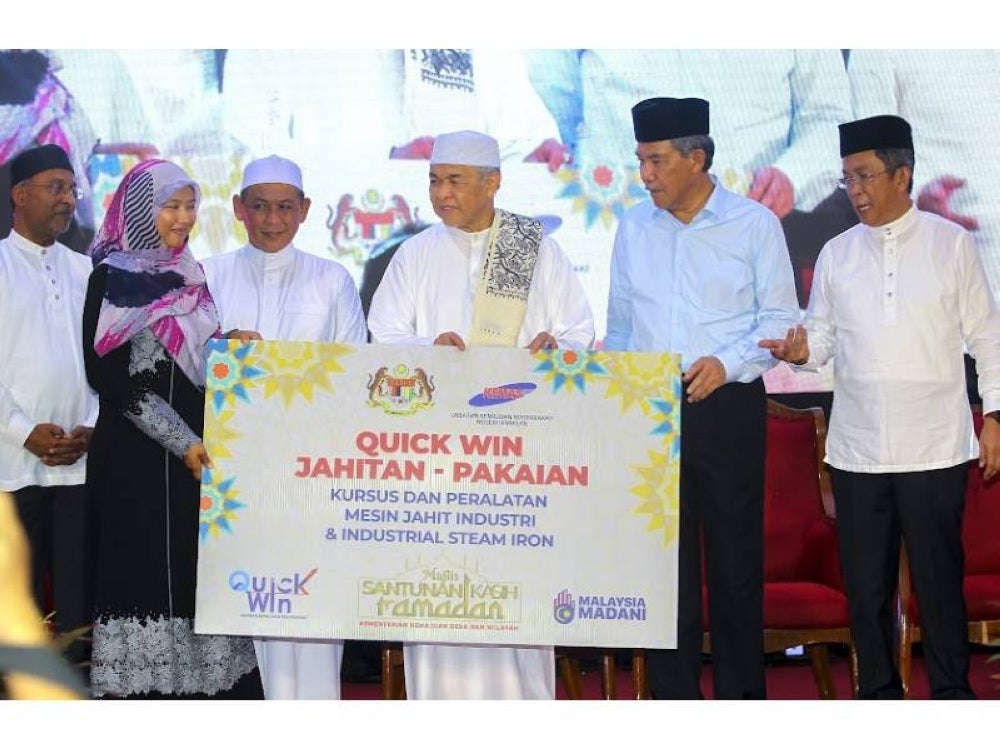 Ahmad Zahid(tiga dari kanan) menyerahkan bantuan kit peralatan dan kursus ‘Quick Win’ KEMAS kepada wakil peserta.