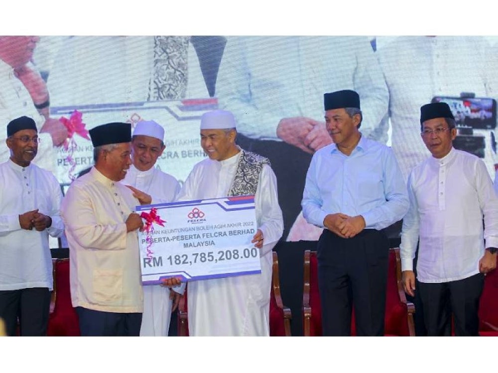 Ahmad Zahid(tiga dari kanan) menyampaikan replika cek kepada wakil peserta Felcra.