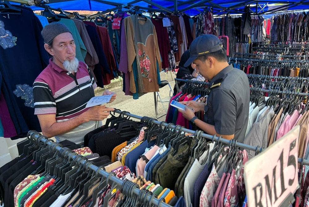Penguat kuasa KPDN melakukan pemeriksaan di sebuah gerai menjual pakaian di bazar raya.