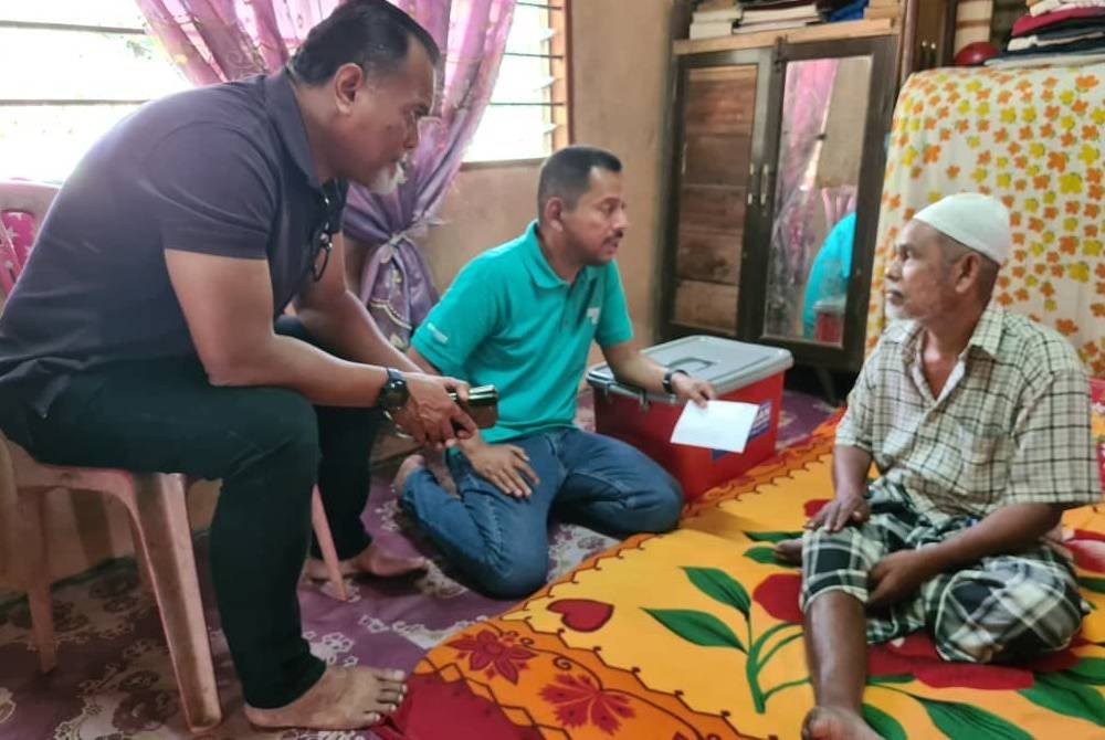 Syaiful Rizal (tengah) dan Rizal (kiri) ketika menyantuni asnaf di sekitar Padang Besar pada Jumaat.