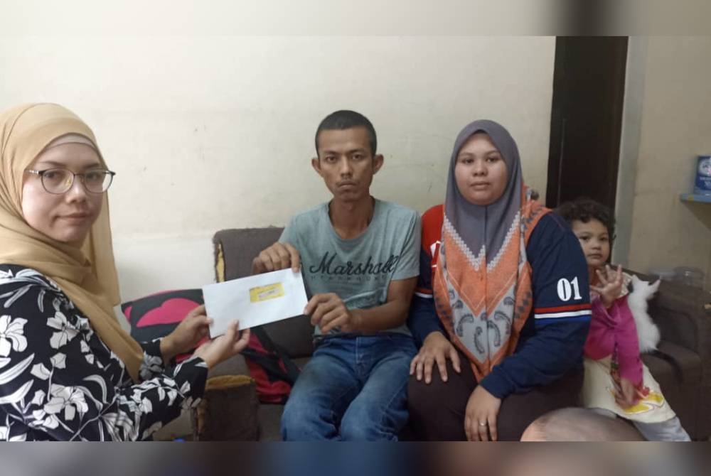 Zulkifli bersama Siti Nuratikah menerima sumbangan wang tunai daripada Yayasan Nur Karangkraf disampaikan Ketua Wartawan Johor, Nor Azura Md Amin di PPR Taman Setia Indah Johor Bahru.