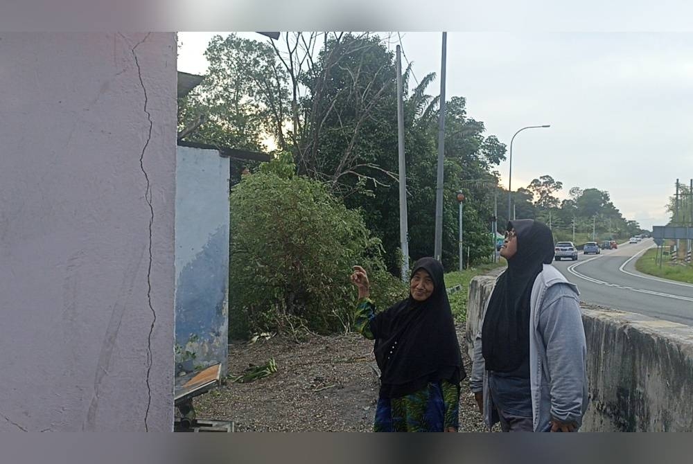 Nurul dan ibunya Rusilah melihat keadaan dinding dapur selepas kejadian rempuhan sebuah lori treler pada Jumaat lalu.