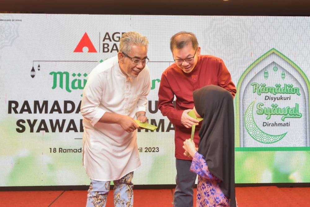 Tengku Ahmad Badli Shah (kanan) bersama Foong Hin menyampaikan sumbangan aidilfitri kepada salah seorang penerima pada Majlis Iftar Agrobank Bersama Asnaf Sabah di Kota Kinabalu, pada Ahad.
