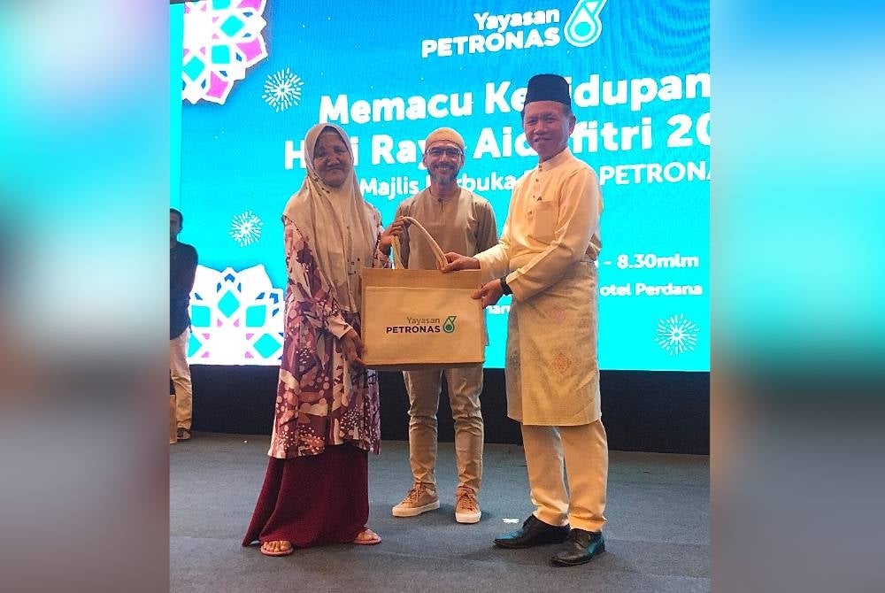 Wan Kamariah (kiri) menerima sumbangan yang disampaikan oleh Said (kanan) sambil diiringi Mohammad Ahmad Shazly (tengah).