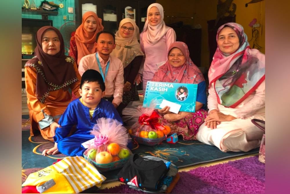 Nora (kiri) yang hadir menyampaikan sumbangan Aidilfitri kepada Muhammad Fariz Iskandar.