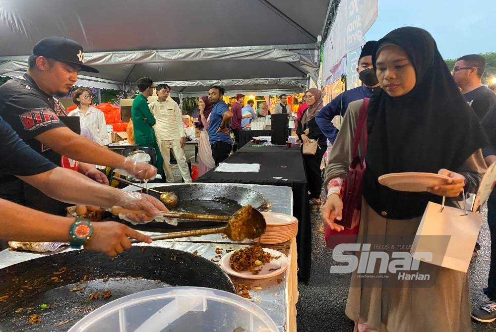 Orang ramai beratur untuk mendapatkan makanan percuma yang tersedia di perkarangan Kompleks Karangkraf.