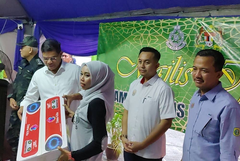 Saifuddin (dua dari kiri) menyampaikan sumbangan kepada salah seorang wakil penduduk semasa Majlis Berbuka Puasa PDRM bersama penduduk Sungai Haji Dorani di Surau Riyadhus, Sungai Besar pada Rabu.