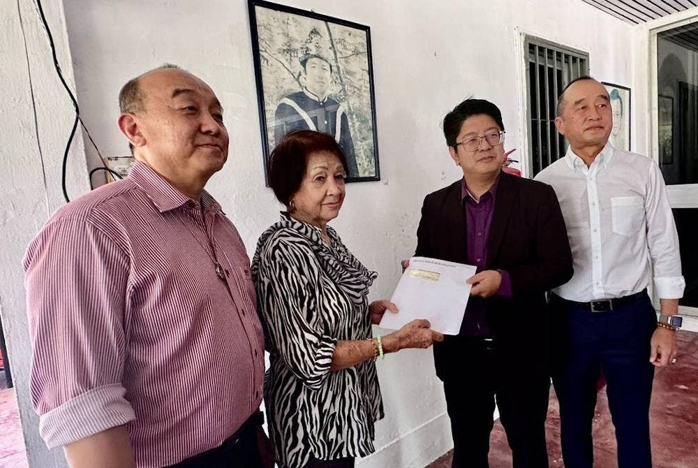 Ewon (dua dari kanan) menyampaikan salinan laporan akhir tragedi Double Six kepada Nancy yang turut ditemani anaknya Donald (kanan) di kediaman mereka Kampung Hungap, Penampang.