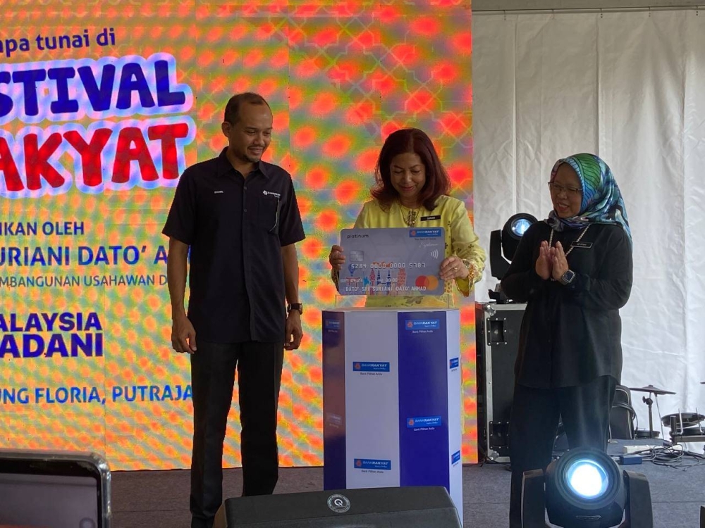 Suriani (tengah) meletakkan replika kad ATM Bank Rakyat sebagaj simbolik perasmian Festival Rakyat.