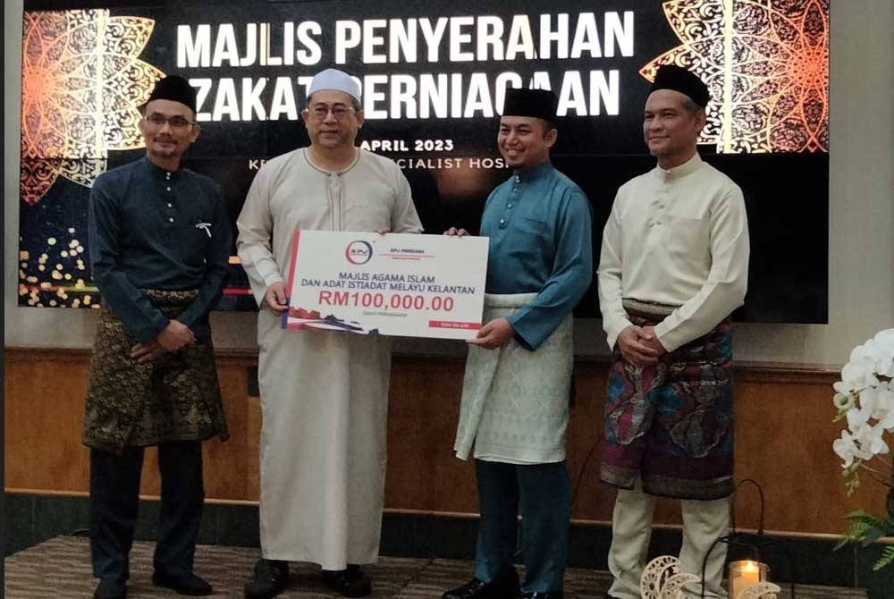 Roslan (dua dari kiri) menyampaikan zakat perniagaan kepada Ameer Azeezy.