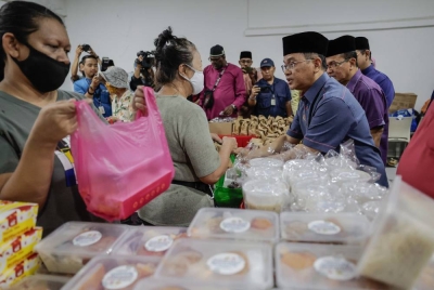 Dr Mohd Na'im Mokhtar (kanan) menyampaikan pek makanan kepada golongan gelandangan pada Program Santuni Gelandangan Chow Kit di Pusat Pembelajaran dan Komuniti Chow Kit pada Jumaat. - Foto Bernama