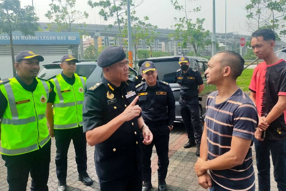 Erick (tengah) meluangkan masa beramah mesra dengan seorang pemandu bas yang menjalani ujian di depoh perhentian bas TBS pada Isnin.