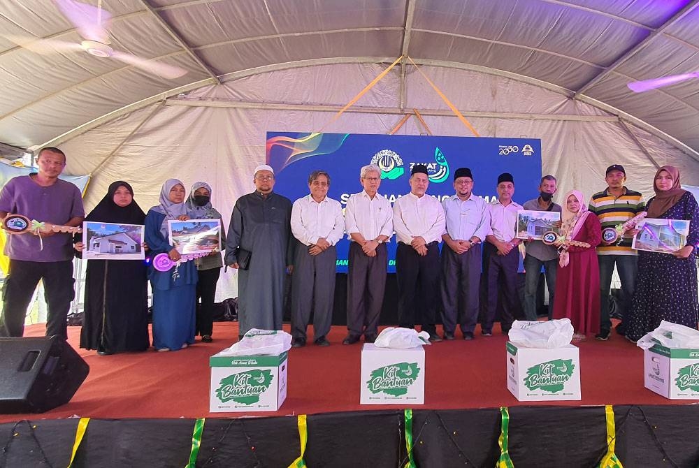 Penerima bantuan rumah bergambar bersama Ahmad Zakiyuddin (lapan dari kanan) selepas majlis pelancaran reka bentuk baharu rumah Skim Inapan Kasih dan penyampaian saguhati Aidilfitri di Kampung Jarak Tengah, Tasek Gelugor pada Isnin.