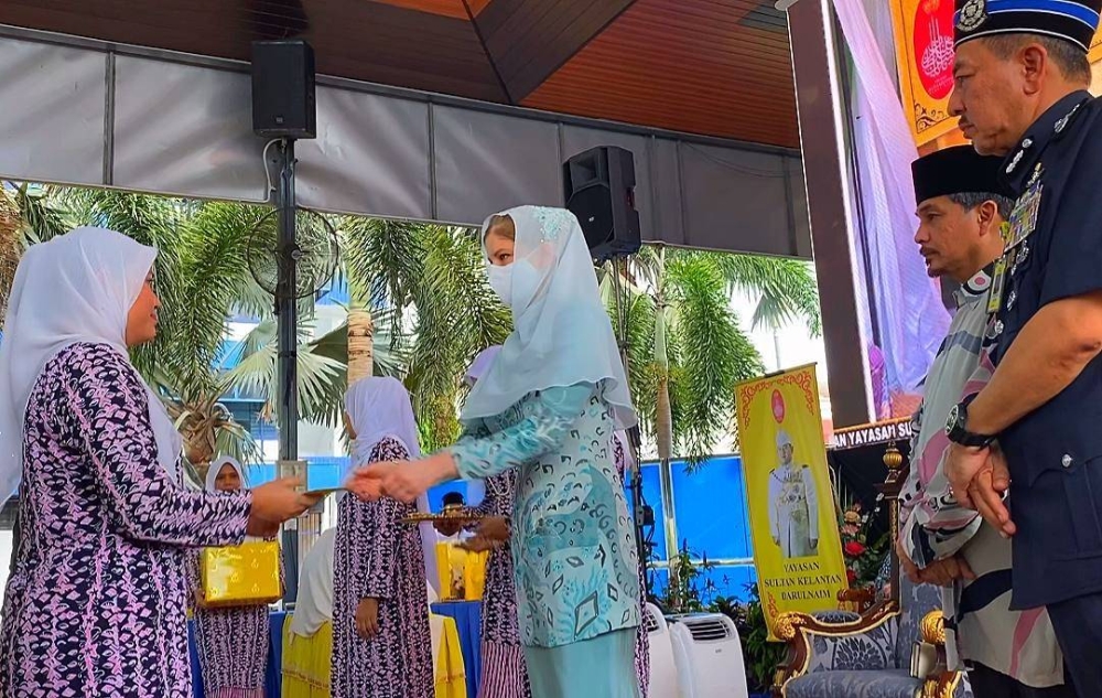 Muhamad Zaki (kanan) mengiringi Sultanah Kelantan mengurniakan sumbangan kepada penerima pada majlis pengurniaan sumbangan Yayasan Sultan Kelantan Darulnaim di IPK Kelantan, Kota Bharu pada Selasa.