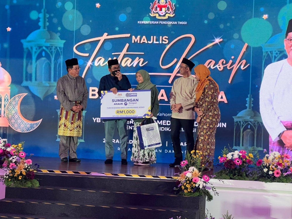 Puteri Nur Baheera (tengah) menerima replika sumbangan Simpan SSPN Prime daripada Mohamed Khaled (dua dari kiri).