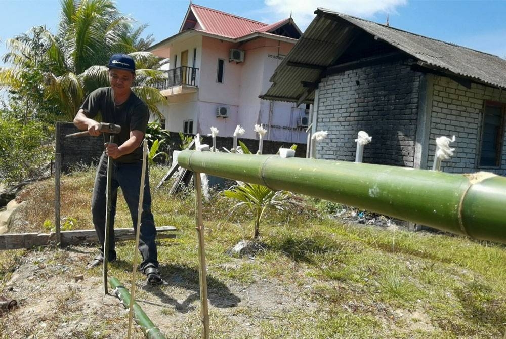 Mohamad Azmizan sedang menyiapkan tempahan pelita buluh.