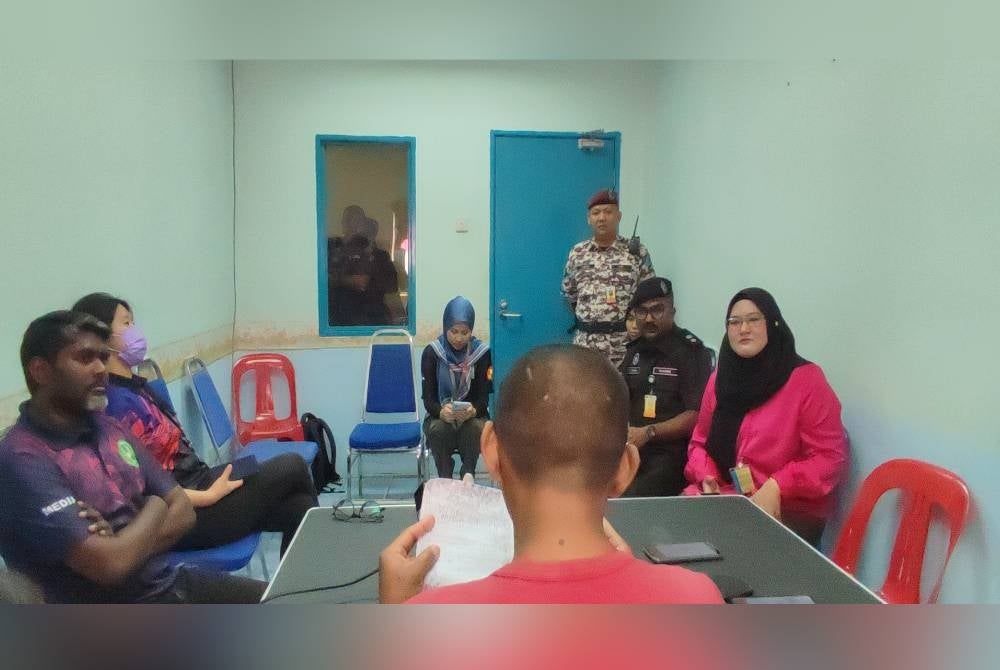 Amir membaca kad raya ditulisnya dihadapanS Tanabal (dua dari kanan) dan pemberita pada program Pelepasan Banduan Secara Berlesen (PBSL) Ihsan Madani (Kepulangan Yang Dinanti) sempena Hari Raya Aidilfitri 2023 di Penjara Pokok Sena, di sini, pada Rabu.