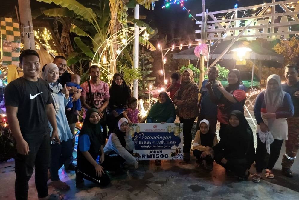 Adik-beradik Azlina Ibrahim bersama ibu mereka bergambar di halaman rumah yang dihias dengan pelita, lampu dan pelbagai dekorasi Hari Raya Aidilfitri yang diperbuat daripada bahan kitar semula seperti aluminium, tong cat, buluh, kayu dan kotak ketika tinjauan di rumah mereka di Jalan Pay Lengkung, Merlimau Pasir di sini malam ini.