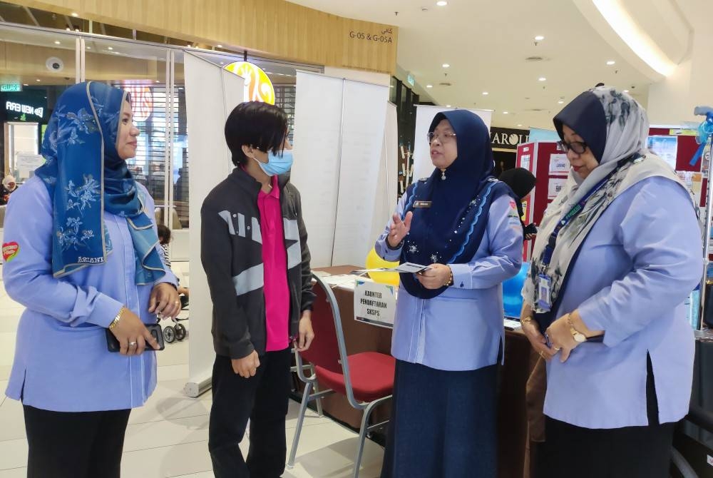 Farihah (dua dari kanan) menerangkan mengenai caruman Perkeso kepada orang ramai.