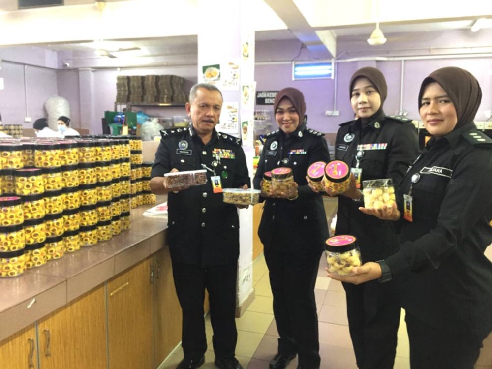 Wan Sani (kiri) dan anggota penjara menunjukkan biskut raya yang dihasilkan penghuni Penjara Pengkalan Chepa.