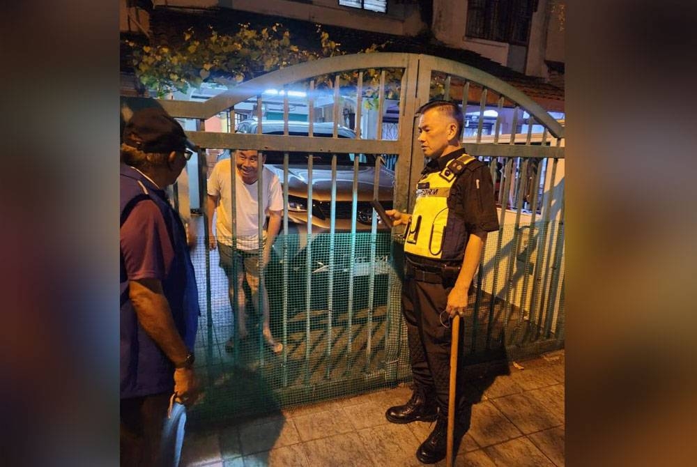 Seorang pegawai polis bersama pasukan sukarelawan bertanya khabar kepada penghuni di sebuah taman perumahan.