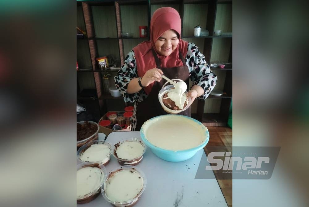 Umil Izzah sedang memasukkan topping cheese ke dalam kek yang dibuatnya.