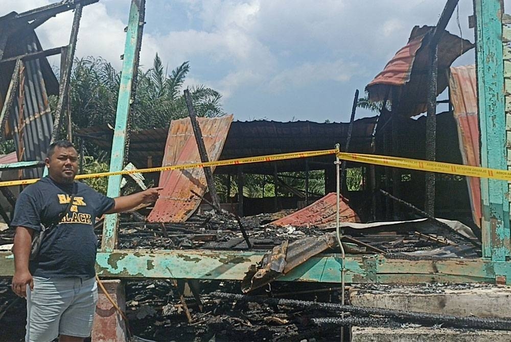 Mohd Shahrul menunjukkan rumah yang hangus terbakar di Kampung Seri Bunian, Pontian.