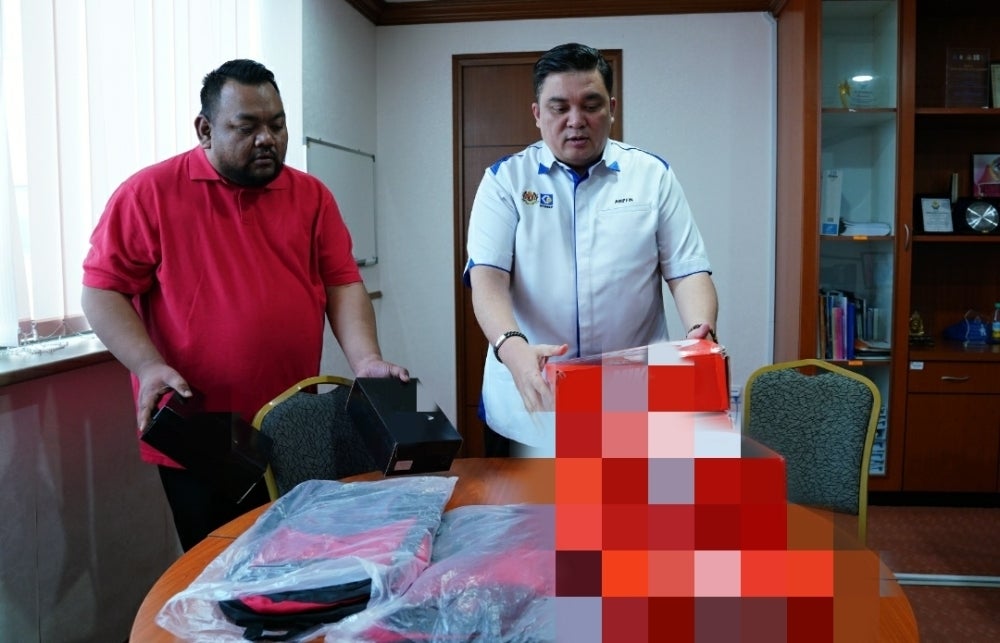 Ariffin (kanan) menunjukkan barangan jenama mewah tiruan yang dirampas pihaknya. 