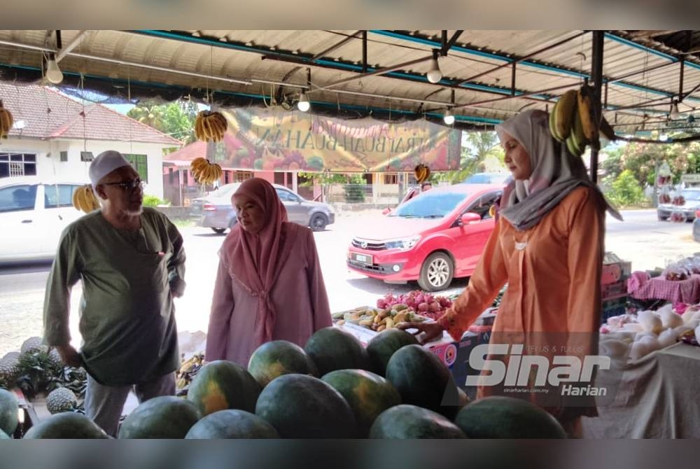 Noris Maznida melayan pelanggan di kedai buahnya di Kampung Pauh Lima, Bachok.