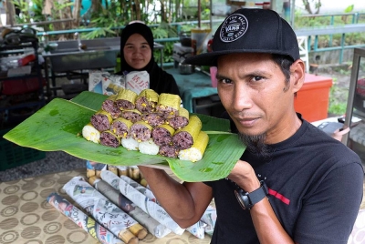 Peniaga, Shamsur Ezam Mohd Afandi, 38, (kanan) menunjukkan pelbagai variasi lemang ketika tinjauan Bernama di gerai lemangnya di Klebang Putra semalam.