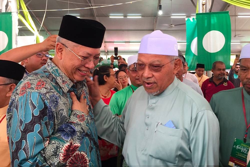 Ahmad (kanan) meraikan kehadiran Annuar pada Majlis Rumah Terbuka Aidilfitri Pas Kelantan di Kota Bharu pada Sabtu.