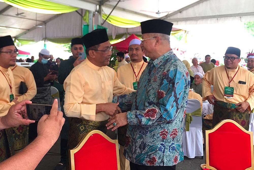 Annuar (kanan) bersalaman dengan Takiyuddin di majlis sambutan hari raya pada Sabtu.