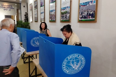 Pengundi menandakan kertas undi yang diberikan pegawai bertugas di salah sebuah pusat pengundi di bandar Tashken.