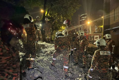 Anggota Bomba sedang mencari pengawal keselamatan yang tertimbus dalam insiden tanah runtuh di Taman Seputeh, di sini, pada Khamis.