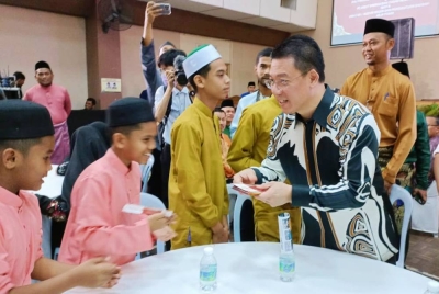 Kor Ming menyerahkan duit raya kepada tetamu yang hadir sempena Majlis Rumah Terbuka Aidilfitri daerah Hilir Perak di Dewan Bandaran Teluk Intan pada Jumaat.