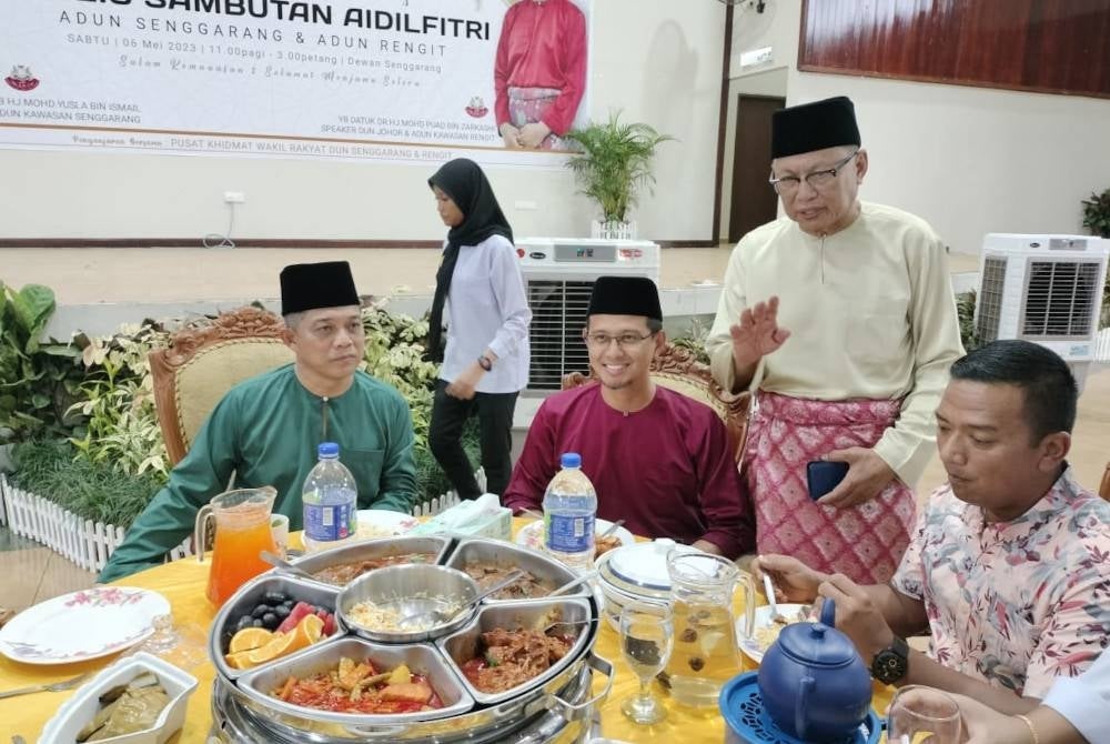 Mohd Puad (berdiri) melayan tetamu yang hadir Rumah Terbuka Aidilfitri DUN Rengit dan Senggarang, di Dewan Senggarang, Batu Pahat pada Sabtu.