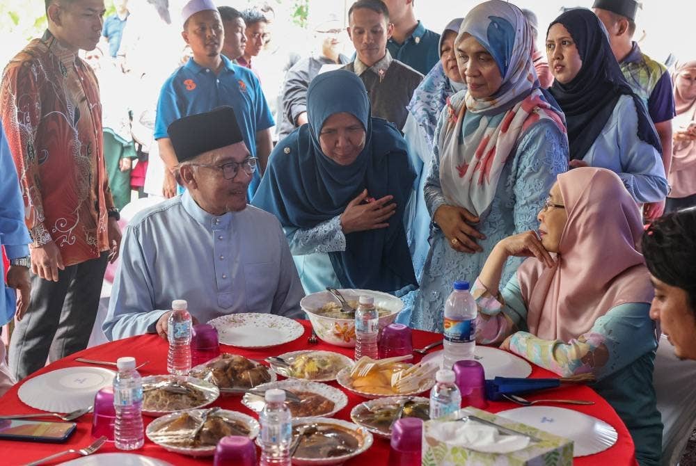 Anwar bersama Dr Wan Azizah Wan ketika menghadiri majlis kenduri kahwin di Kampung Pelet, pada Sabtu. - Foto Bernama
