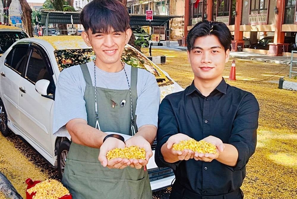 Aidil Afizudin (kanan) dan rakannya, Syahmi Asyraf Mokhtar (kiri) menunjukkan bunga-bunga angsana.