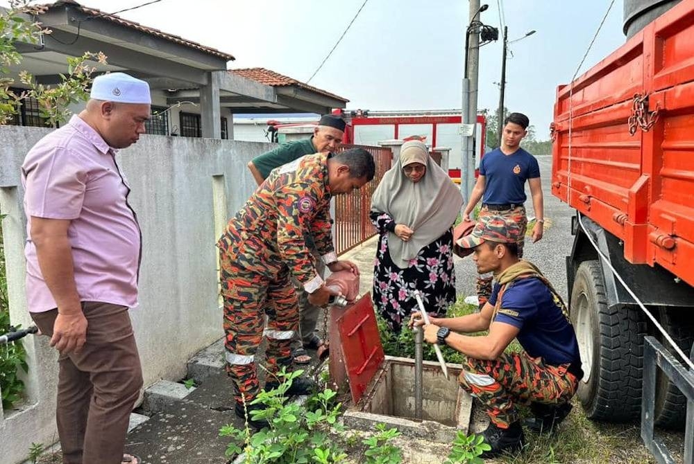Siti Zailah (au milieu) voit des pompiers préparer l'approvisionnement en eau des bouches d'incendie aux résidents.