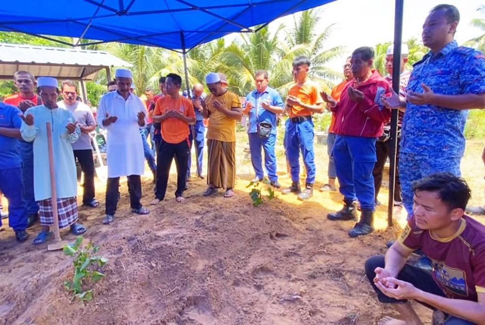 Mohd Adzhar (kanan) hadir di pengkebumian Lans Korperal Mohd Idris di Tanah Perkuburan Islam Kemasin.