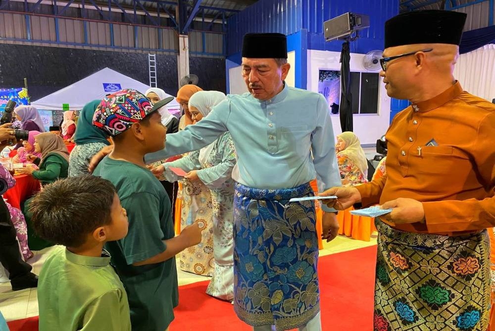 Muhamad Zaki (deuxième à droite) et Zaizul Rizal ont présenté un don de duit raya aux enfants du personnel de l'IPD Pasir Puteh qui ont assisté à la célébration d'Aidilfitri.