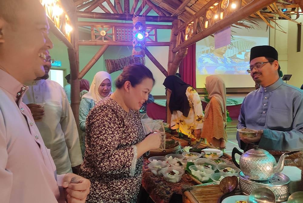 Syamsul Badrin (kanan) beramah mesra bersama pegawainya di gerai juadah ketika sambutan Majlis Hari Raya di Kompleks KDN, Kuala Lumpur pada Rabu.