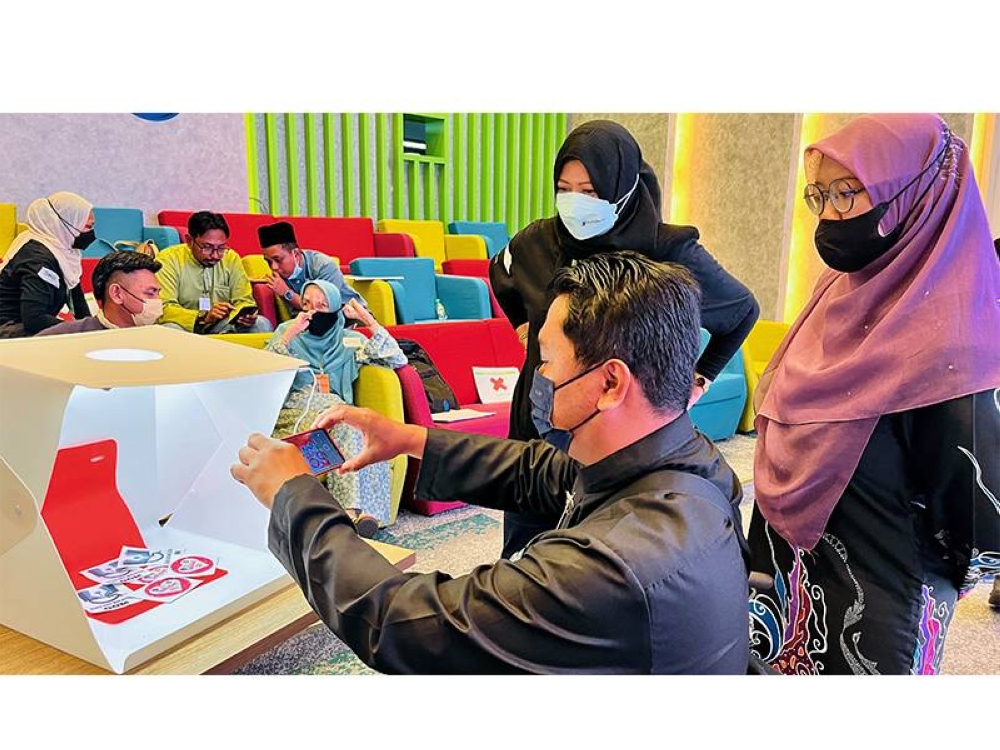 Peserta Maxis eKelas Usahawan mencuba fotografi digital untuk produk mereka semasa bengkel.