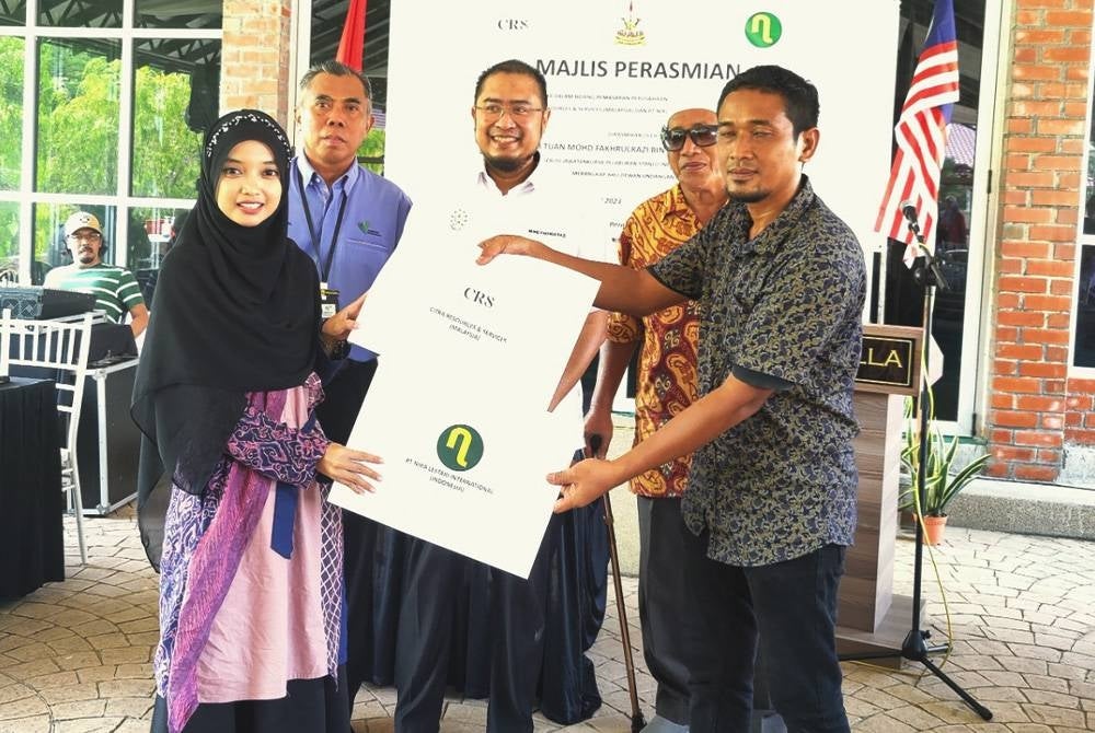 Mohd Fakhrulrazi (belakang tengah) melihat pertukaran dokumen antara wakil Citra Resources and Services (depan kanan) dan PT Nira Lestari International Indonesia (depan kiri) pada Majlis Kerjasama Pemasaran Produk Berasaskan Kelapa di Dewan Daza Villa, Kampung Perepat, Klang di sini pada Khamis.