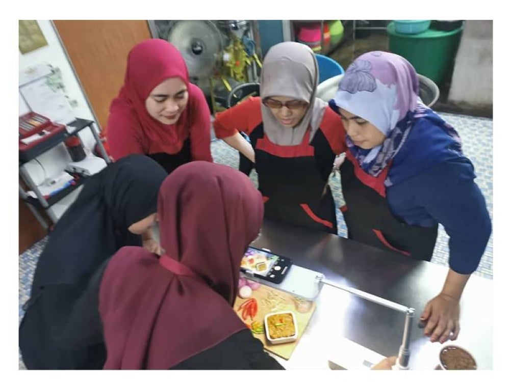  Pekerja di kilang Tokey Sambal Hitam sedang mencipta kandungan untuk dimuat naik dalam kedai e-dagang mereka.