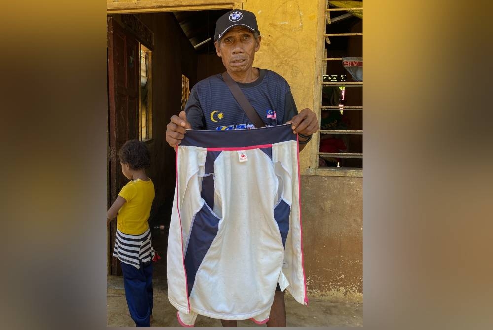 Asin menunjukkan baju milik anaknya yang didakwa maut selepas diserang harimau, Selasa lalu. - Foto Bernama