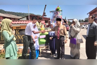 Mohamad Azwan (dua dari kiri) bersalam dengan Suhaimi pada Ahad sempena hari pertama memulakan persekolahan di SMK Dabong.