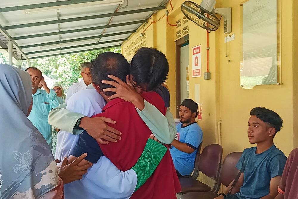 Nasaruddin memeluk anaknya sebaik tiba di Unit Forensik Hospital Kampar bagi proses tuntutan jenazah isteri dan anak-anaknya.