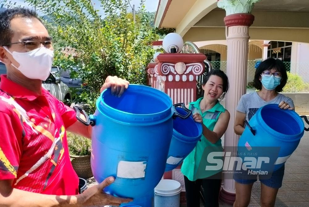 Cheah Chin (kiri) dan jirannya bersiap sedia bersama tong kosong menunggu lori menghantar bekalan air setelah empat hari terputus bekalan.
