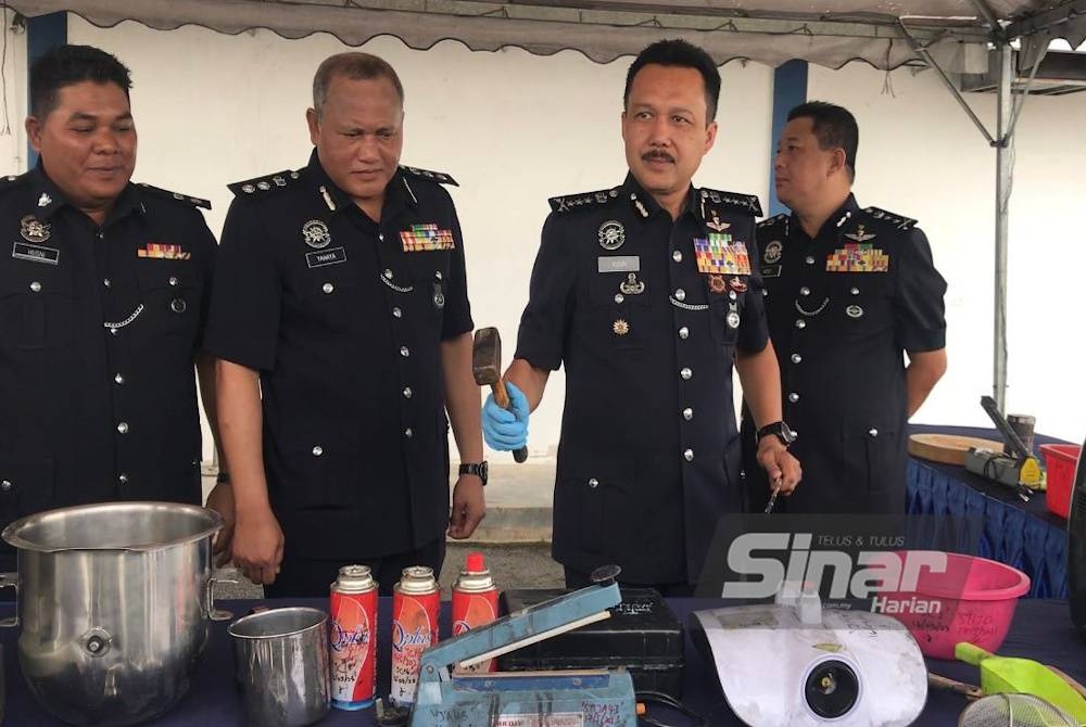 Mohd Yusri (dua dari kanan) menunjukkan peralatan memproses dadah yang dirampas PDRM di Jelapang pada Selasa.